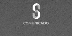 Sobre um fundo cinza escuro há um S estililizado da marca do SINJUS-MG, na cor branca, abaixo dele está escrito "Comunicado".
