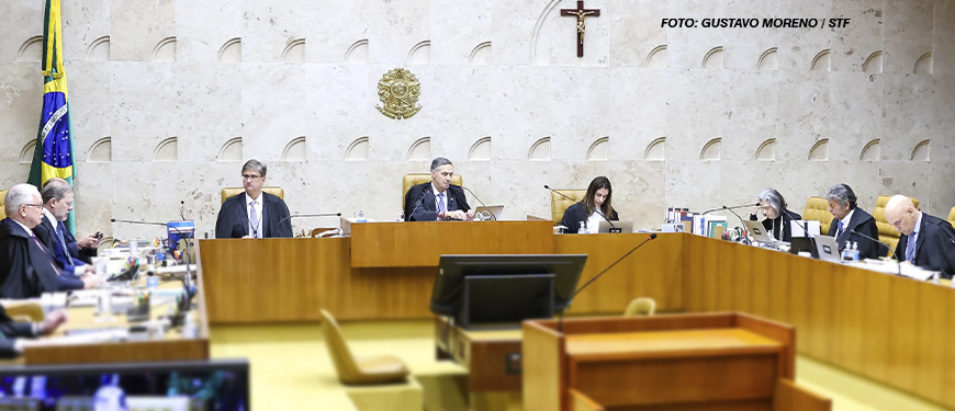 As imagens mostram uma sessão no plenário do STF do Brasil, com ministros sentados em uma bancada semicircular posicionados em cadeiras de madeira. Ao fundo, na parede, está o brasão do Brasil e uma cruz. Alguns monitores exibem uma pessoa discursando, e há pessoas na plateia assistindo à sessão. Em duas das imagens, aparece sobreposto um texto em letras grandes, destacando a expressão "Nota pública à decisão do STF sobre o regime jurídico único: um erro fatal" em vermelho e preto, enfatizando uma crítica sobre a decisão do tribunal.