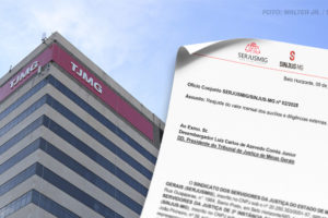 A imagem mostra o edifício do TJMG. Em frente ao prédio, há um documento parcialmente dobrado em destaque, contendo os logotipos dos sindicatos SERJUSMIG e SINJUS-MG, além de texto formal que informa o envio de um ofício solicitando o reajuste de auxílios e verbas indenizatórias.