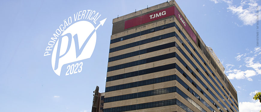 Fotografia de um grande prédio com fachada bege e janelas espelhadas escuras. No topo do edifício, há placas vermelhas com a sigla "TJMG" (Tribunal de Justiça de Minas Gerais). O céu azul com algumas nuvens aparece ao fundo. Na parte superior da imagem, há um logotipo branco com a inscrição "Promoção Vertical PV 2023" e uma seta apontando para cima. Conteúdo textual: CARREIRA - TJMG divulga decisão acerca dos pedidos de reconsideração da PV 2023.