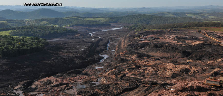 Imagem acessível: Paisagem com verdes montanhas ao fundo, no primeiro plano está parte da cidade de Brumadinho destruída pela lama com rejeitos tóxicos, proveniente do rompimento da barragem em 2019.