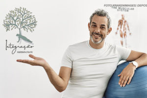 Homem de cabelos grisalhos, barba curta, usando uma camiseta branca e calça preta, está sentado ao lado de uma bola de pilates azul. Ele está sorrindo e com uma das mãos estendida em um gesto amigável. Ao fundo, há uma imagem anatômica de um corpo humano e o logotipo da "Integração Fisioterapia e Pilates", que mostra uma árvore com um tronco estilizado como uma pessoa fazendo uma postura de yoga.