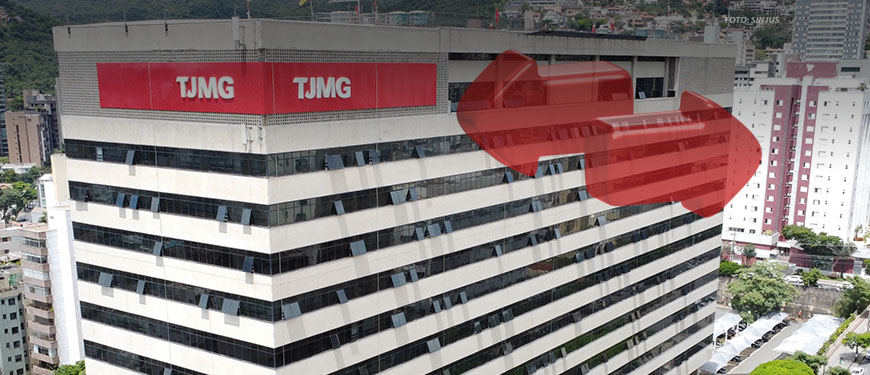 Edifício do Tribunal de Justiça de Minas Gerais (TJMG), com a fachada destacando duas áreas em vermelho na parte superior, onde está o logotipo do TJMG em placas visíveis. O edifício está localizado em uma área urbana com outros prédios ao redor